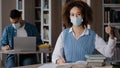 Young girl student in medical mask sits at desk in library preparing to lesson writing note in notebook looking at Royalty Free Stock Photo