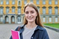 Young girl student posing outdoors, background of educational building