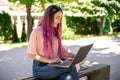 Young girl is studying in the spring park, sitting on the wooden bench and browsing on her laptop Royalty Free Stock Photo