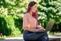 Young girl is studying in the spring park, sitting on the wooden bench and browsing on her laptop Royalty Free Stock Photo