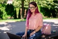 Young girl is studying in the spring park, sitting on the wooden bench and browsing on her laptop Royalty Free Stock Photo