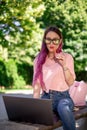 Young girl is studying in the spring park, sitting on the wooden bench and browsing on her laptop Royalty Free Stock Photo