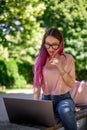 Young girl is studying in the spring park, sitting on the wooden bench and browsing on her laptop Royalty Free Stock Photo