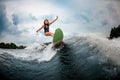 Young girl stunts on a wakeboard in the river near forest Royalty Free Stock Photo