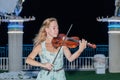 The young girl in the summer evening plays for passers-by on the violin on the waterfront of Nahariya, Israel