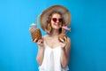 Young girl in a sun hat and glasses drinks tropical cocktails from pineapple and coconut on a blue isolated background, relaxing Royalty Free Stock Photo