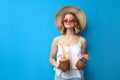 Young girl in a sun hat and glasses holds tropical cocktails made of pineapple and coconut on a blue isolated background, relaxing Royalty Free Stock Photo