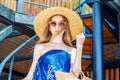 Young girl in sunglasses in a straw hat goes down the stairs. Summer mood, beach holidays