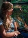 Young girl in sunset lighting traveling in train car and her reflection in window
