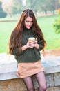 Girl enjoys smell of coffee sitting in autumn park