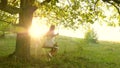 Young girl swinging on a swing on an oak branch in sun. Dreams of flying. Happy childhood concept. Beautiful girl in a