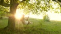 Young girl swinging on a swing on an oak branch in sun. Dreams of flying. Happy childhood concept. Beautiful girl in a