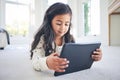 Young girl, tablet and game app or cartoon streaming online with internet, elearning and relax on carpet in house. Watch Royalty Free Stock Photo