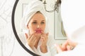 A young girl takes care of her face in the bathroom, a woman stands in front of the mirror puts lip patches on her face