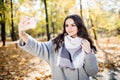 Young girl takes a selfie on the backgroung autumn park