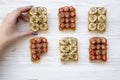 Young girl takes vegan toast with fruits, seeds, peanut butter over white wooden background, top view. Dieting concept.