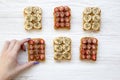 Young girl takes vegan toast with fruits, seeds, peanut butter over white wooden background, top view. Dieting concept.