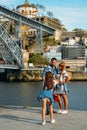 Young girl takesk a picture of couple at the Ribeira in the Douro River bank near the Dom Luis I Bridge, Porto, Portugal Royalty Free Stock Photo