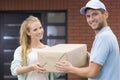 Girl taking a delivery form handsome courier in blue uniform Royalty Free Stock Photo