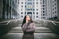 Young girl talking on mobile phone in courtyard business center. girl with long dark hair dressed in winter jacket in cold weather Royalty Free Stock Photo