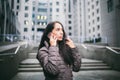 Young girl talking on mobile phone in courtyard business center. girl with long dark hair dressed in winter jacket in cold weather Royalty Free Stock Photo