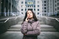 Young girl talking on mobile phone in courtyard business center. girl with long dark hair dressed in winter jacket in cold weather Royalty Free Stock Photo