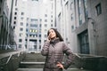 Young girl talking on mobile phone in courtyard business center. girl with long dark hair dressed in winter jacket in cold weather Royalty Free Stock Photo