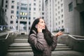 Young girl talking on mobile phone in courtyard business center. girl with long dark hair dressed in winter jacket in cold weather Royalty Free Stock Photo