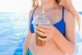 A young girl teenager holds and drink a colored cold non-alcoholic cocktail in her hand against the background of the sea beach Royalty Free Stock Photo