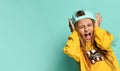 Pretty fashionable young teenager with a lovely smile posing in a baseball cap and yellow hoodie on a blue background Royalty Free Stock Photo