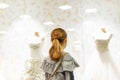 A young girl, a teenager, stands near the window of a wedding salon and looks at wedding dresses, introducing family life Royalty Free Stock Photo