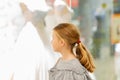 A young girl, a teenager, stands near the window of a wedding salon and looks at wedding dresses, introducing family life Royalty Free Stock Photo