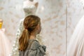 A young girl, a teenager, stands near the window of a wedding salon and looks at wedding dresses, introducing family life Royalty Free Stock Photo