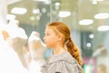 A young girl, a teenager, stands near the window of a wedding salon and looks at wedding dresses, introducing family life Royalty Free Stock Photo