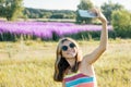 Young girl teenager walking in nature is photographed on mobile smartphone, sunny summer day background purple lavender field Royalty Free Stock Photo