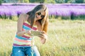 Young girl teenager walking in nature photographs flower plant on mobile smartphone, background sunny summer day purple lavender Royalty Free Stock Photo