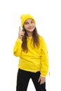 A young  girl teeneger wearing yellow hoody and knitted hat  proves something by raising his index finger up, isolated Royalty Free Stock Photo