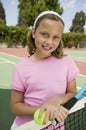 Young girl with tennis racket and ball by net at tennis court portrait Royalty Free Stock Photo