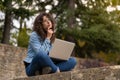 Young girl thinking what to type on her laptop sitting in the park Royalty Free Stock Photo