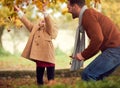 Young Girl Throwing Autumn Leaves In The Air As She Has Fun Playing In Garden With Parents