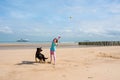 young girl throwing a tennis ball to her dog on the sunny beach Royalty Free Stock Photo