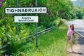 Young girl at the Tighnabruaich sign at the road entrance to the village in Argyll and Bute