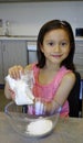 Young Girl Tipping Cake Mix Into A Bowl.