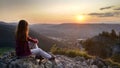 Young girl tourist looks at sunset over Zakopane from the top of the mountain, Poland, High Tatras