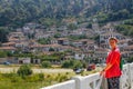 Young girl tourist in a pink blouse stands on a bridge over the river Lumi i Osumit in the city of Berat Royalty Free Stock Photo