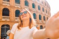 Young tourist woman in sunglasses making selfie photo on her smartphone in front of the famous Plaza de Toros de
