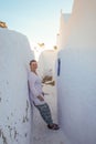 A young girl tourist in white clothes smiles and fills on the white walls of the city of Fira. Royalty Free Stock Photo