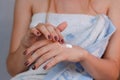 Young girl in towel putting cream on hands. Royalty Free Stock Photo