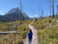 A young girl on a trail hiking on three falls trail with Saint Mary Lake below in Montana, USA.