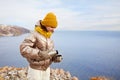 A young girl traveler pours hot tea into a mug from a thermos in nature. Mountain winter landscape.